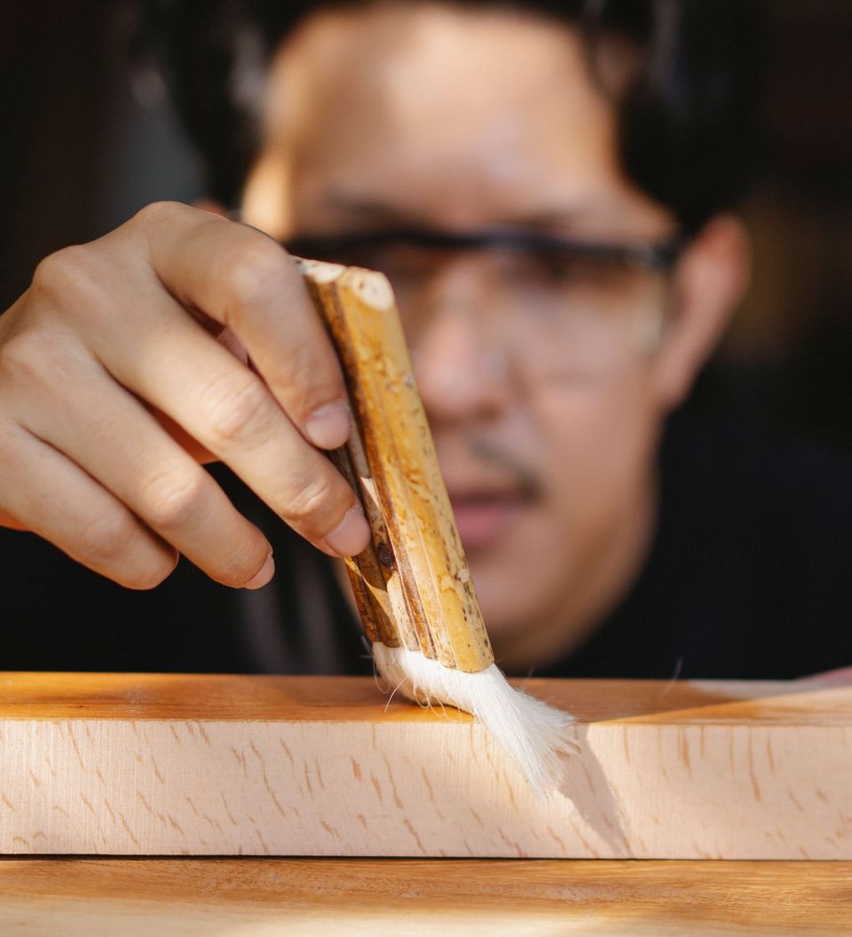 An artisan varnishing a handmade wooden piece in his workshop