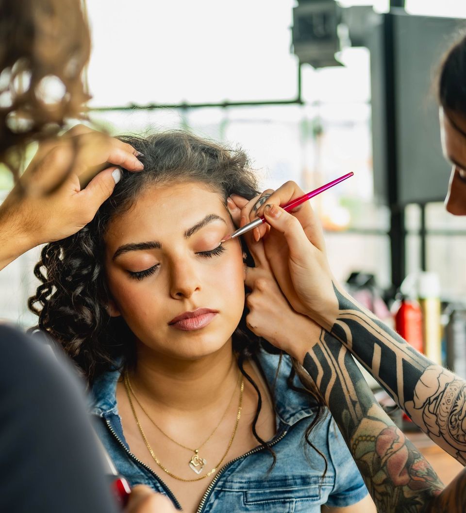 A makeup artist doing a client's eye makeup in a studio